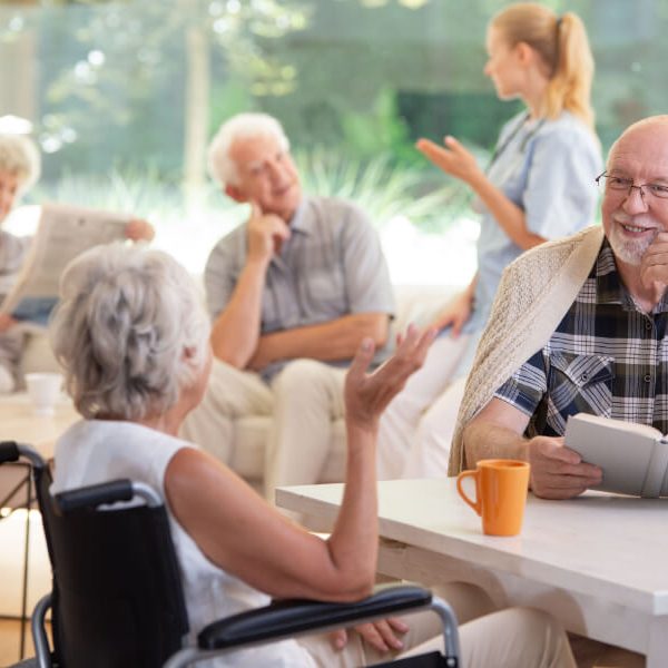 smiling-senior-man-with-book-talking-with-elderly-JNZQ9K2.jpg